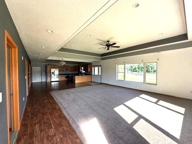 832 E Main St, Central City, IA 52214 - unfurnished living room with a raised ceiling, recessed lighting, dark wood-style floors, and ceiling fan