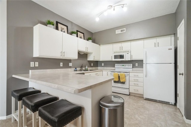 3028 Center Point Rd NE Unit 201, Cedar Rapids, IA 52402 - kitchen with white appliances, a peninsula, light countertops, a breakfast bar area, and white cabinets
