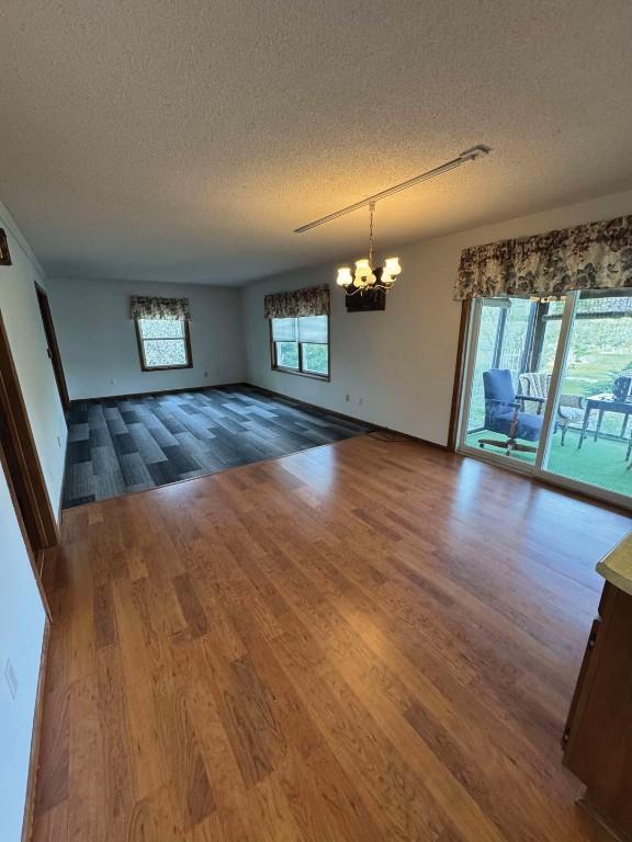 1852 215th St, Manchester, IA 52057 - spare room with a textured ceiling, a chandelier, and wood finished floors
