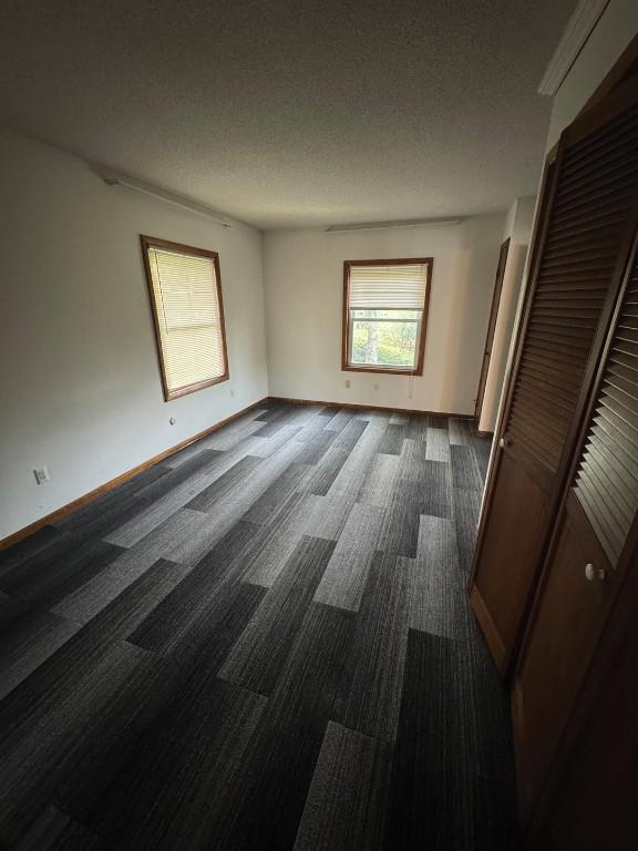 1852 215th St, Manchester, IA 52057 - unfurnished bedroom with dark carpet, a textured ceiling, and a closet