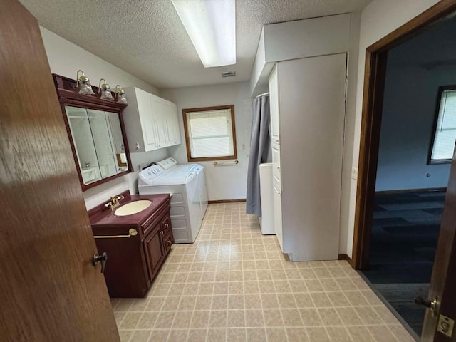 1852 215th St, Manchester, IA 52057 - laundry area with light flooring, washing machine and clothes dryer, a textured ceiling, and cabinet space