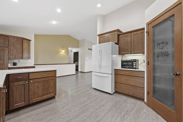 2089 117th Ct, Kalona, IA 52247 - kitchen with freestanding refrigerator, lofted ceiling, light countertops, light wood-type flooring, and recessed lighting