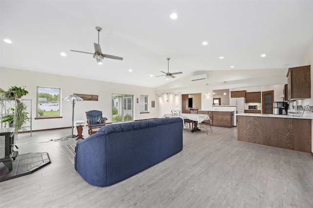 2089 117th Ct, Kalona, IA 52247 - living room with vaulted ceiling, an AC wall unit, light wood-style flooring, ceiling fan, and recessed lighting