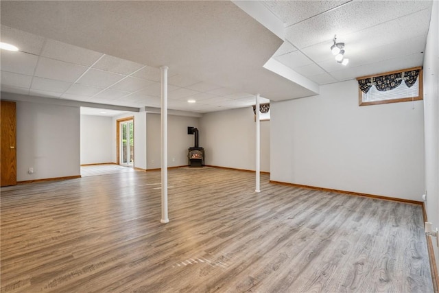 5524 Cimarron Ct, Marion, IA 52302 - below grade area featuring a wood stove, a drop ceiling, and light wood-type flooring