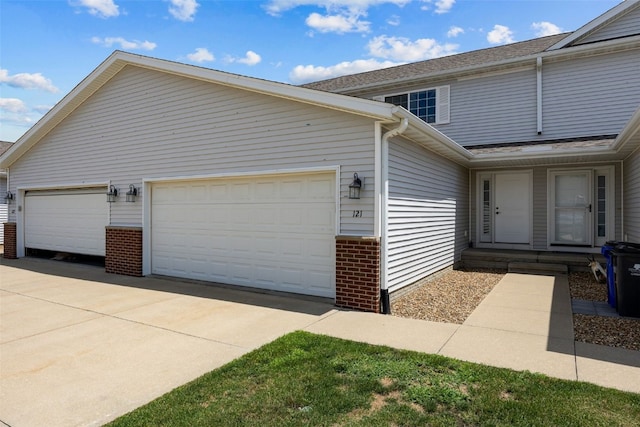 121 Woodstone Ln SW, Cedar Rapids, IA 52404 - view of property exterior featuring brick siding, a garage, concrete driveway, and a shingled roof