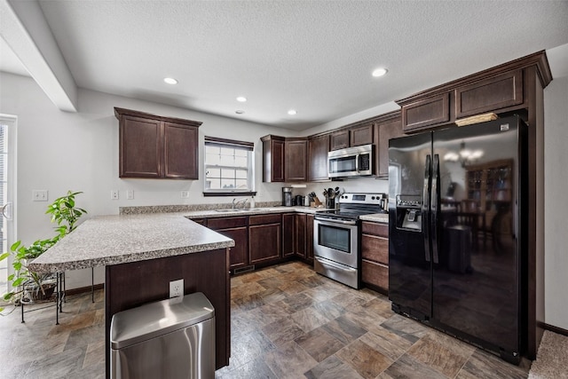 121 Woodstone Ln SW, Cedar Rapids, IA 52404 - kitchen featuring appliances with stainless steel finishes, a peninsula, dark brown cabinets, stone finish floors, and recessed lighting