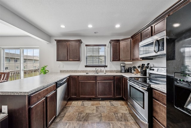 121 Woodstone Ln SW, Cedar Rapids, IA 52404 - kitchen featuring stainless steel appliances, recessed lighting, a peninsula, plenty of natural light, and dark brown cabinetry