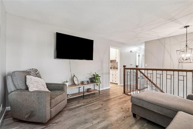 6808 Kelburn Ln NE, Cedar Rapids, IA 52402 - living room featuring a chandelier, light wood-style flooring, and a textured ceiling