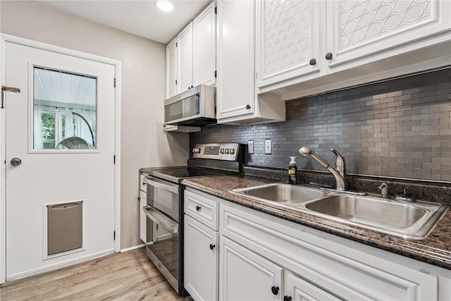 6808 Kelburn Ln NE, Cedar Rapids, IA 52402 - kitchen featuring stainless steel appliances, white cabinets, decorative backsplash, and light wood finished floors