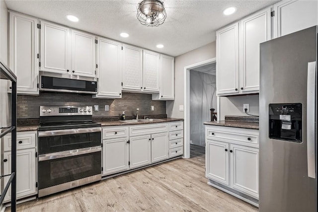6808 Kelburn Ln NE, Cedar Rapids, IA 52402 - kitchen with appliances with stainless steel finishes, backsplash, white cabinets, light wood finished floors, and recessed lighting