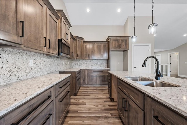 468 Chamber Dr, Anamosa, IA 52205 - kitchen with stainless steel microwave, wood finished floors, light stone countertops, decorative light fixtures, and backsplash