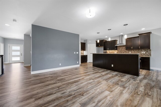 4310 Carpenter Rd NE, Cedar Rapids, IA 52411 - kitchen with wall chimney range hood, wood finished floors, backsplash, dark brown cabinets, and open floor plan