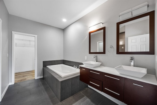 4310 Carpenter Rd NE, Cedar Rapids, IA 52411 - bathroom featuring a garden tub, double vanity, a walk in closet, recessed lighting, and tile patterned flooring