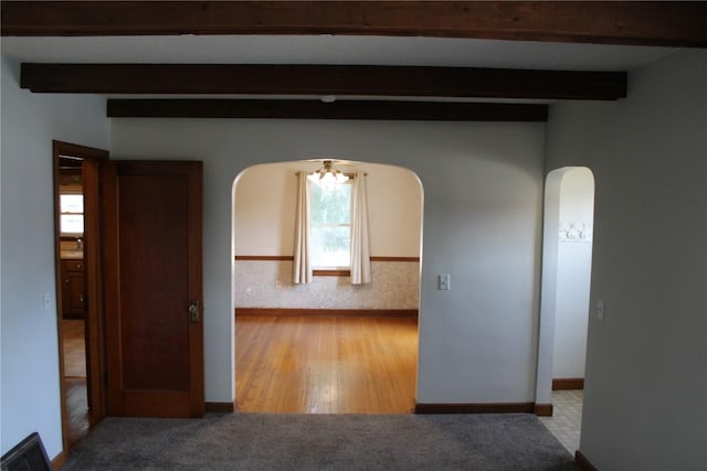 302 S Main St, Monticello, IA 52310 - carpeted spare room with arched walkways, beam ceiling, and wood finished floors