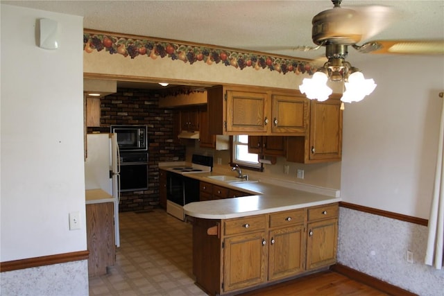302 S Main St, Monticello, IA 52310 - kitchen featuring black appliances, light countertops, brown cabinets, a peninsula, and under cabinet range hood