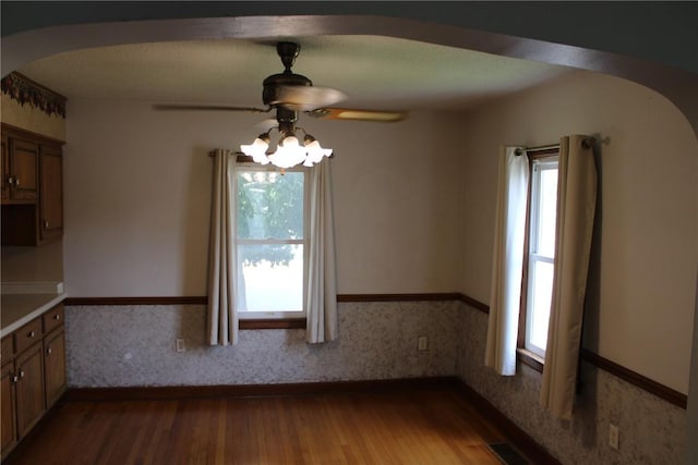 302 S Main St, Monticello, IA 52310 - unfurnished dining area with arched walkways, a ceiling fan, and wood finished floors