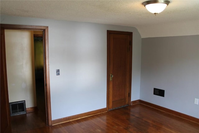 302 S Main St, Monticello, IA 52310 - empty room featuring dark wood-type flooring and a textured ceiling