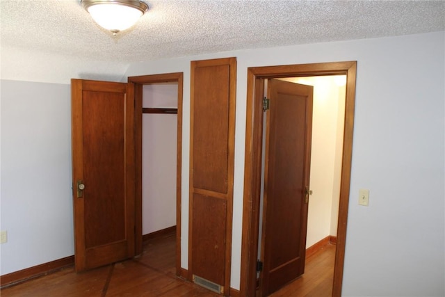 302 S Main St, Monticello, IA 52310 - unfurnished bedroom featuring wood finished floors, a textured ceiling, and multiple closets