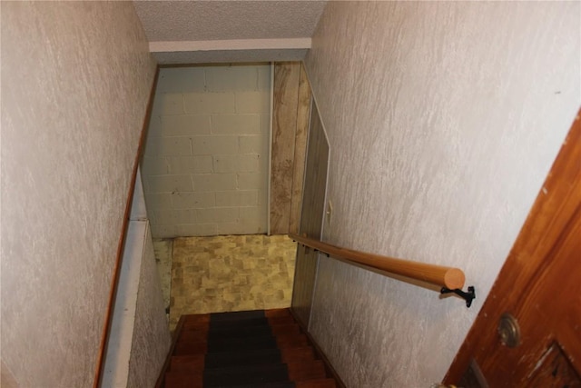 302 S Main St, Monticello, IA 52310 - staircase featuring a textured ceiling and concrete block wall
