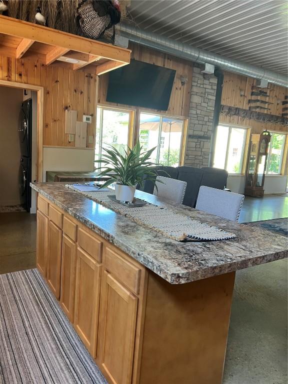 101 Canyon Rd, Montezuma, IA 50171 - kitchen featuring wood walls, a kitchen island, dark stone counters, and open floor plan
