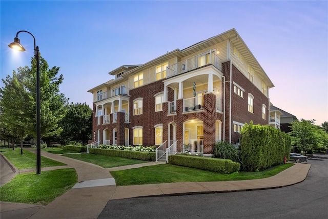 1138 Swisher St, Iowa City, IA 52245 - view of front facade with a balcony, a front lawn, brick siding, and covered porch