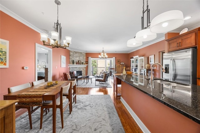 1138 Swisher St, Iowa City, IA 52245 - dining room with a chandelier, a stone fireplace, dark wood-style flooring, and ornamental molding