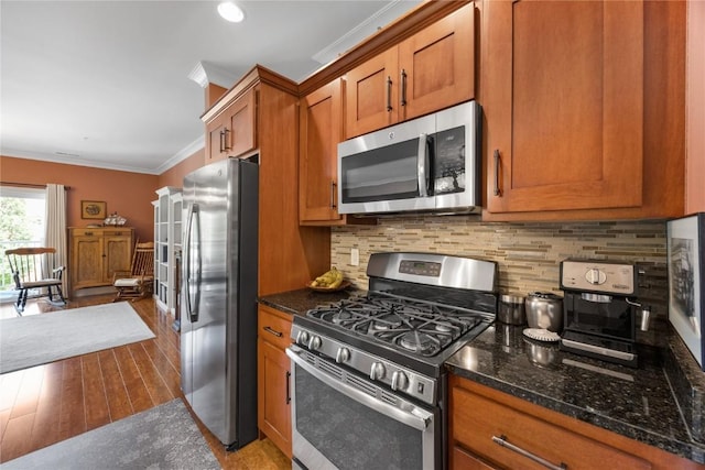 1138 Swisher St, Iowa City, IA 52245 - kitchen featuring stainless steel appliances, brown cabinets, ornamental molding, tasteful backsplash, and dark stone counters
