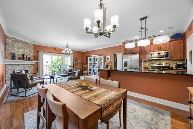 1138 Swisher St, Iowa City, IA 52245 - dining room with a chandelier, ornamental molding, dark wood-style floors, recessed lighting, and a stone fireplace