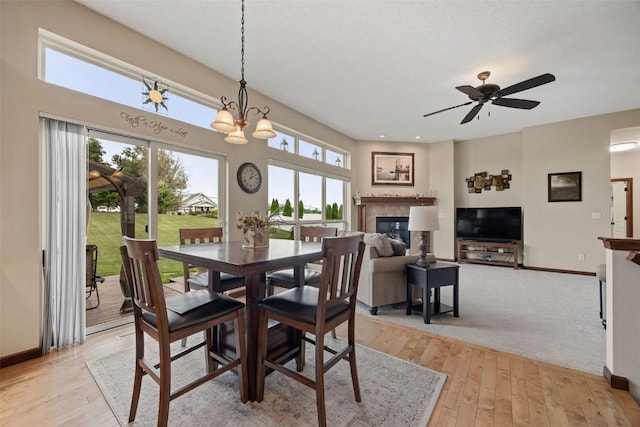 2012 Radcliffe Dr SW, Cedar Rapids, IA 52404 - dining area featuring a tile fireplace, light wood-type flooring, a ceiling fan, and a chandelier