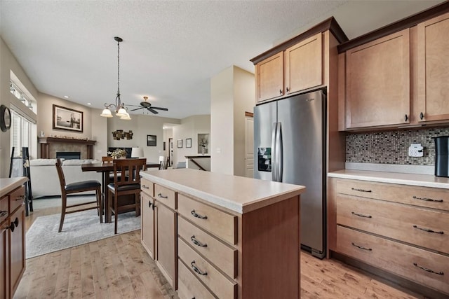2012 Radcliffe Dr SW, Cedar Rapids, IA 52404 - kitchen with stainless steel fridge with ice dispenser, light wood-style flooring, open floor plan, a fireplace, and tasteful backsplash