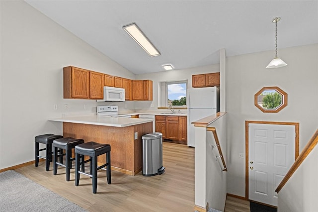 1361 Ozark Rdg, Coralville, IA 52241 - kitchen with white appliances, a peninsula, light wood finished floors, brown cabinetry, and lofted ceiling