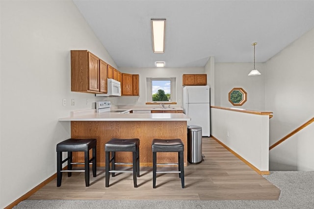 1361 Ozark Rdg, Coralville, IA 52241 - kitchen with white appliances, brown cabinetry, a peninsula, a breakfast bar, and light countertops