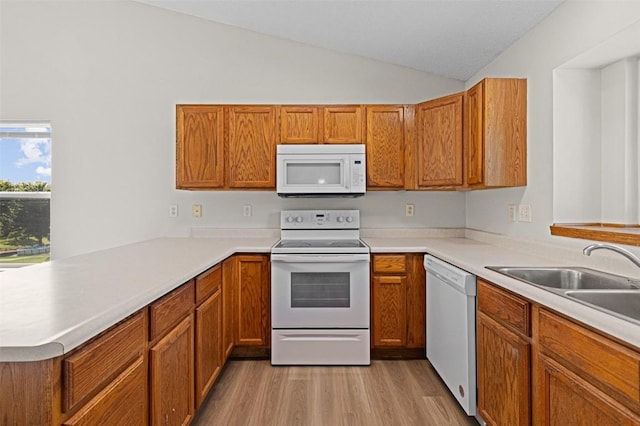 1361 Ozark Rdg, Coralville, IA 52241 - kitchen featuring white appliances, a peninsula, brown cabinetry, vaulted ceiling, and light countertops