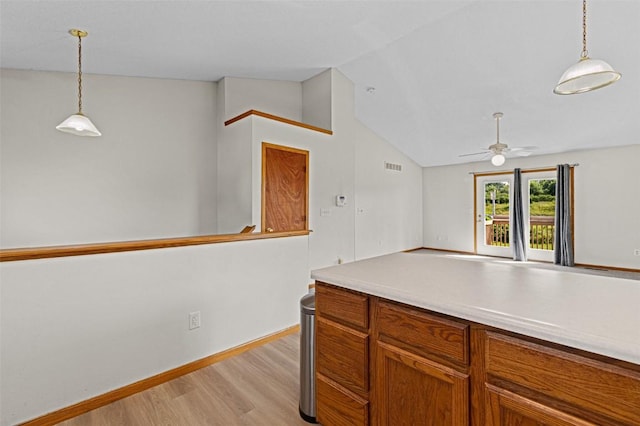 1361 Ozark Rdg, Coralville, IA 52241 - kitchen with light wood-style flooring, lofted ceiling, a ceiling fan, pendant lighting, and brown cabinets