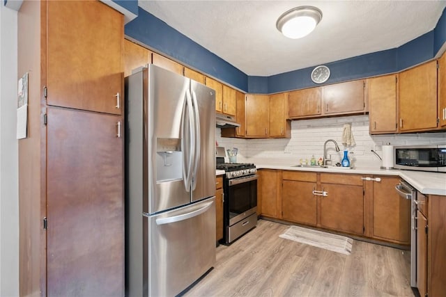 1654 19th St NW, Cedar Rapids, IA 52405 - kitchen with appliances with stainless steel finishes, under cabinet range hood, tasteful backsplash, light wood finished floors, and light countertops