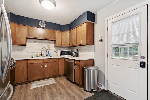 1654 19th St NW, Cedar Rapids, IA 52405 - kitchen featuring appliances with stainless steel finishes, light wood-style floors, brown cabinets, backsplash, and light countertops