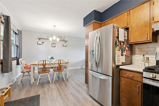 1654 19th St NW, Cedar Rapids, IA 52405 - kitchen with appliances with stainless steel finishes, a chandelier, light wood-type flooring, and brown cabinetry