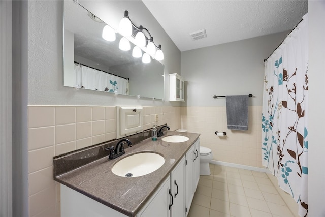 364 Essex Dr NE, Cedar Rapids, IA 52402 - full bathroom featuring tile walls, double vanity, tile patterned floors, a wainscoted wall, and curtained shower