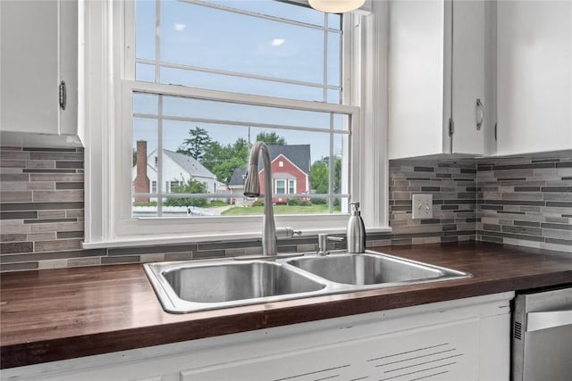 2500 D Ave NE, Cedar Rapids, IA 52402 - kitchen with stainless steel dishwasher, white cabinetry, backsplash, and butcher block counters