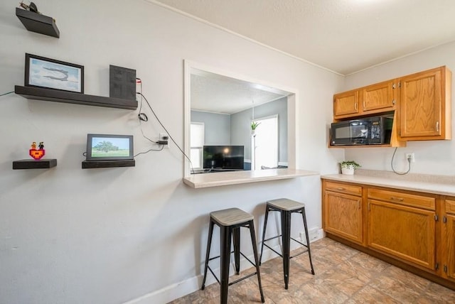 3825 Hart Ct, Cedar Rapids, IA 52402 - kitchen with black microwave, light countertops, brown cabinets, and crown molding
