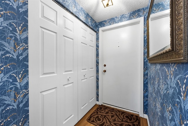 2131 1st Ave Unit 108, Cedar Rapids, IA 52402 - doorway with wallpapered walls, a textured ceiling, and wood finished floors