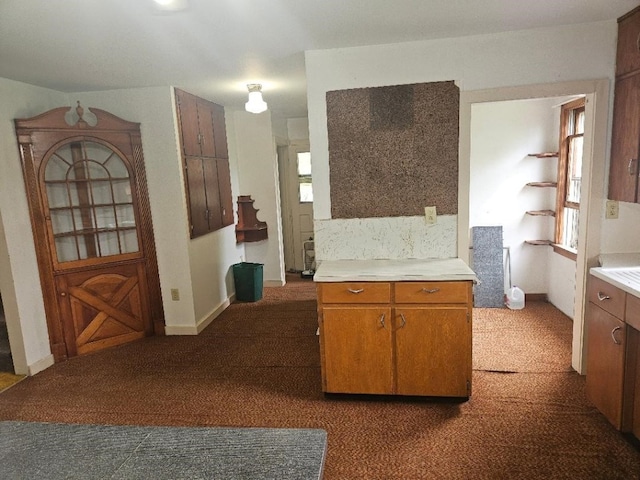 2142 310th Ave, Chelsea, IA 52215 - kitchen featuring light countertops, brown cabinetry, and dark carpet