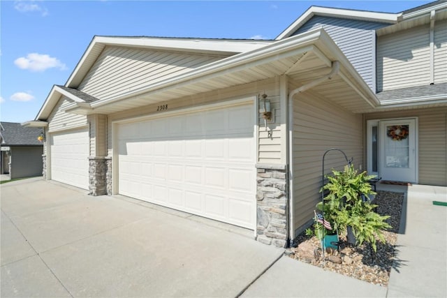 2908 Riviera St SW Unit B, Cedar Rapids, IA 52404 - view of side of home featuring stone siding, concrete driveway, and an attached garage