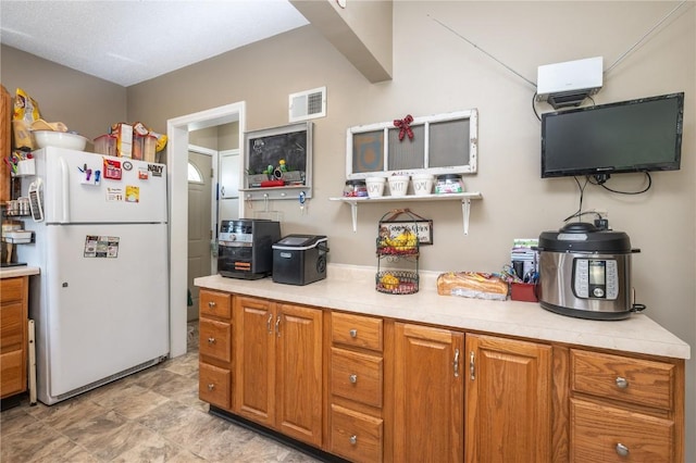 1305 E Ave, Vinton, IA 52349 - kitchen featuring freestanding refrigerator, light countertops, brown cabinetry, and open shelves