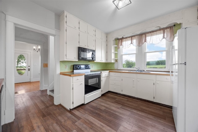 899 Jackson Ave, Mechanicsville, IA 52306 - kitchen featuring black microwave, freestanding refrigerator, electric range oven, dark wood-style flooring, and white cabinetry