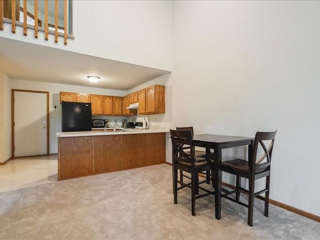 935 74th St NE Unit 5, Cedar Rapids, IA 52402 - kitchen with fridge, under cabinet range hood, a peninsula, a high ceiling, and light countertops