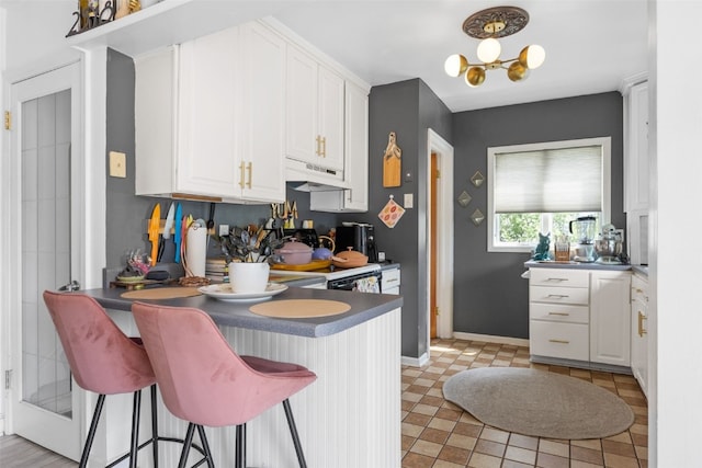 2518 1st Ave NE, Cedar Rapids, IA 52402 - kitchen featuring under cabinet range hood, white cabinetry, and a kitchen breakfast bar