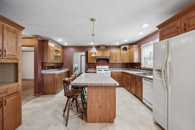204 Northgate St, Shellsburg, IA 52332 - kitchen with white appliances, a center island, washer and dryer, a kitchen bar, and recessed lighting