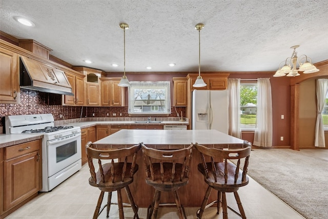 204 Northgate St, Shellsburg, IA 52332 - kitchen featuring white appliances, custom exhaust hood, a center island, a chandelier, and light countertops