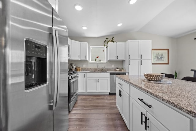 904 Hughes St, Coralville, IA 52241 - kitchen with stainless steel appliances, vaulted ceiling, white cabinets, dark wood finished floors, and light stone countertops